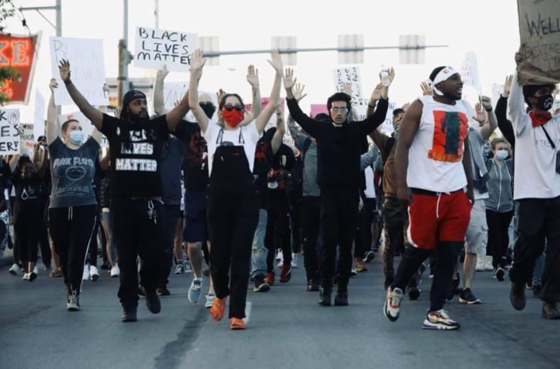 Protesters marching with hands raised and Black Lives Matter signs