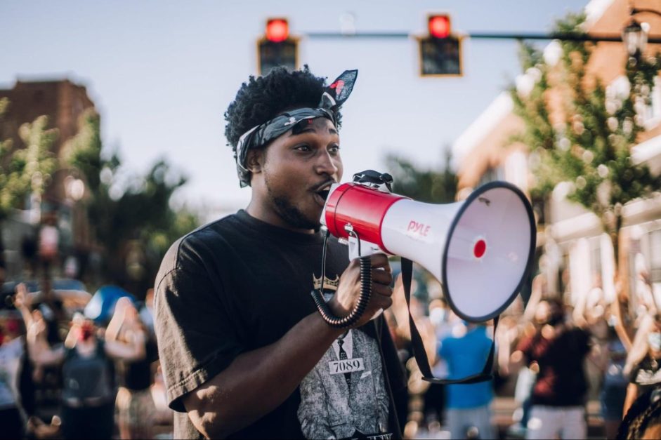 Ebop leading a march through Toledo with a megaphone