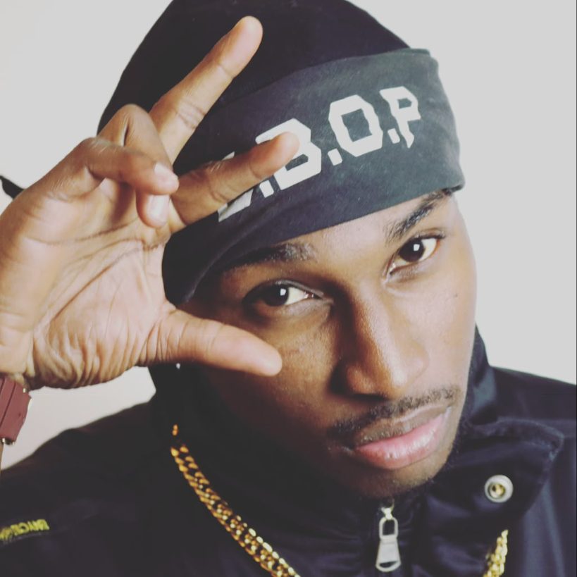 Ebop in an E.B.O.P headband, throwing up a hand sign