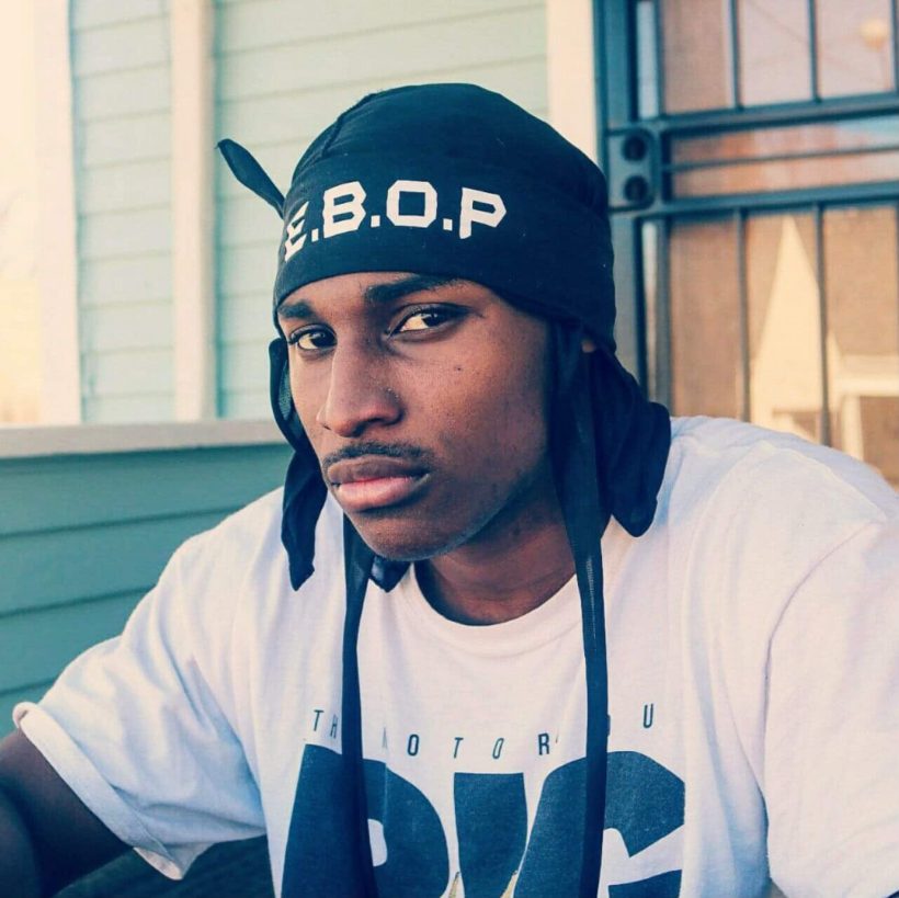 Ebop sitting on a porch in an E.B.O.P durag